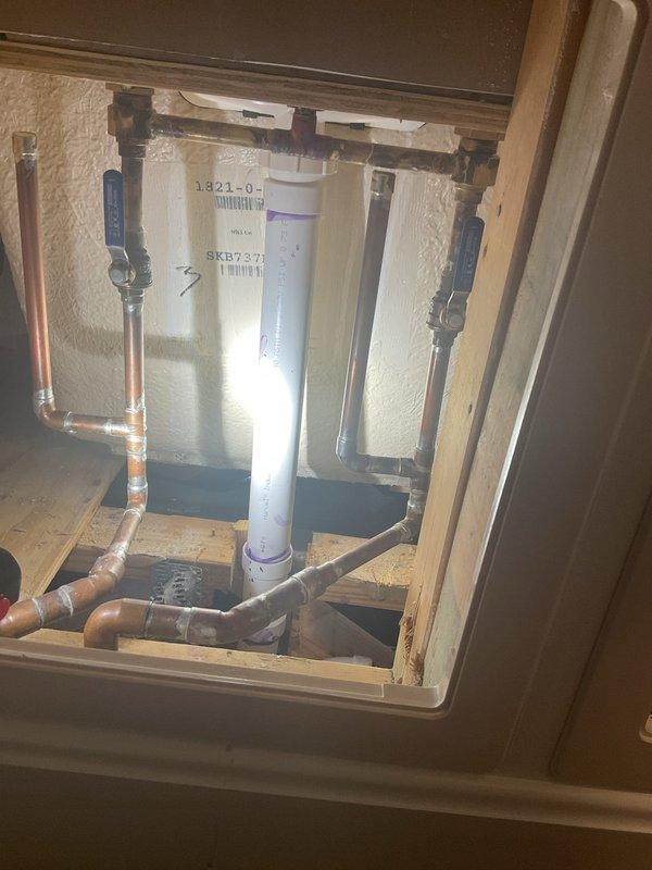 Investigated water damage on ceiling beneath bathroom. Accessed wall cavity to inspect plumbing system, revealing a leaking connection between PVC main line (marked 1321-9/SKB7371) and copper branch pipes. Repaired connection, confirmed proper water flow with no further leakage, and recommended monitoring the ceiling stain for complete drying.