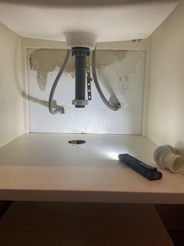 Performed water leak investigation in response to afternoon appointment request. Located source of leak at sink drain connection causing visible water damage to cabinet underside. Inspection of ceiling area revealed water infiltration affecting recessed lighting fixture with notable discoloration and deterioration of surrounding drywall.