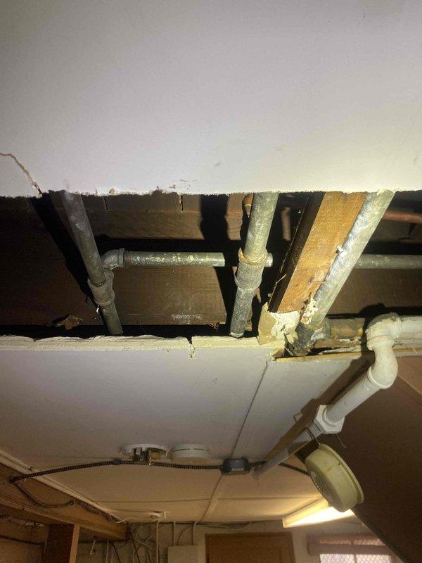 Responded to water leak in basement affecting ceiling and bathroom wall. Located source of leak in corroded galvanized and copper pipe connections, causing significant water damage to ceiling drywall and bathroom wall structure behind tiles. Replaced damaged pipe sections, installed new PVC drain components, and secured all connections to eliminate leakage points.