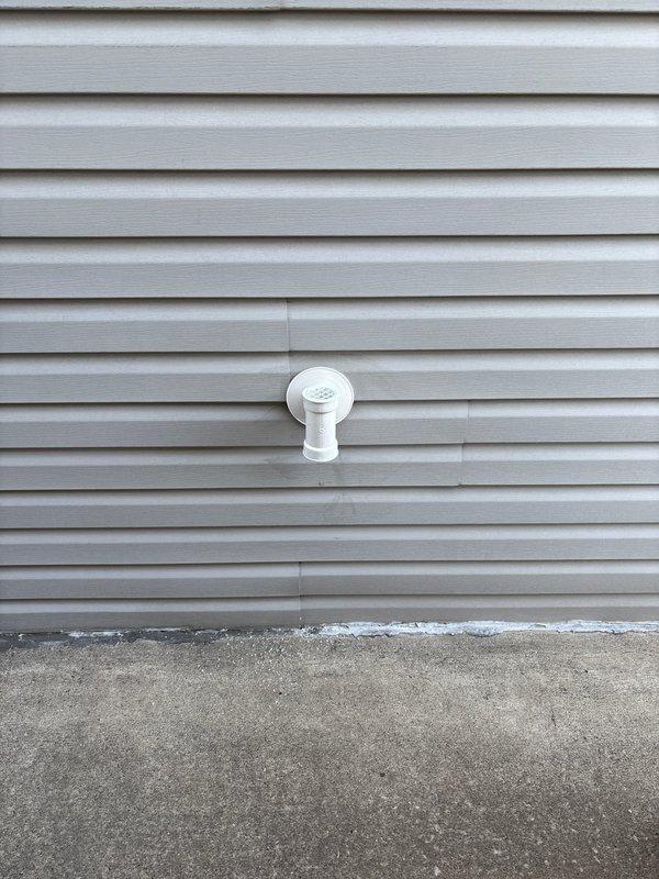 Completed installation of exterior vent for client's home ventilation system. Mounted white plastic vent fixture with square base plate and circular center to exterior light gray vinyl siding, ensuring proper sealing and secure attachment. Job originally sold by Jon.