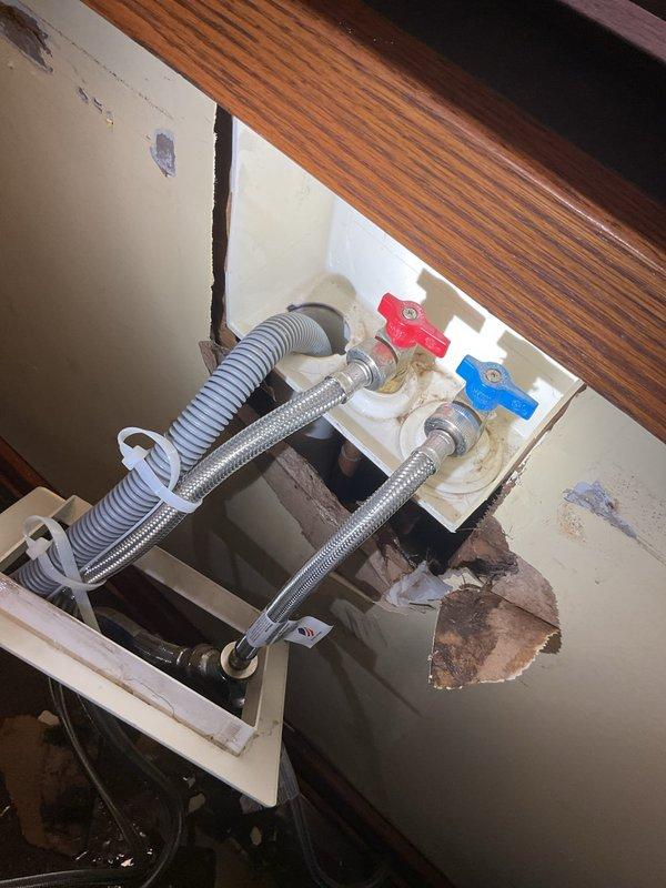Performed commercial estimate for plumbing repairs beneath sink fixture with significant wall damage. Inspection revealed deteriorated drywall around hot and cold water supply lines, exposed fiberglass insulation between wall studs, and compromised plumbing connection box. Documented extensive water damage requiring remediation and potential cabinet/wall reconstruction.