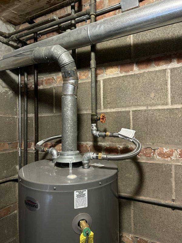 Completed galvanized pipe repair on water line connected to tanked water heater. Installed new metal flexible connector lines with brass fittings and secured proper connections to existing plumbing system. Verified integrity of exhaust ventilation system with 90-degree elbow joint connecting to horizontal vent pipe, ensuring installation meets code requirements.