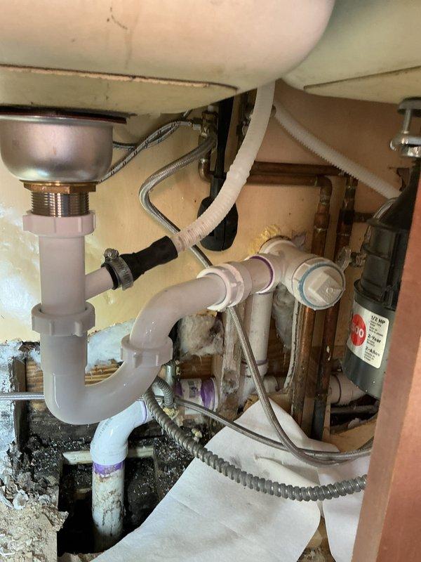 Accessed kitchen wall cavity to investigate reported drain leak. Exposed and inspected plumbing system, including P-trap assembly, PVC and copper piping connections. Identified and repaired leaking drain section, addressing water damage to surrounding wall material.