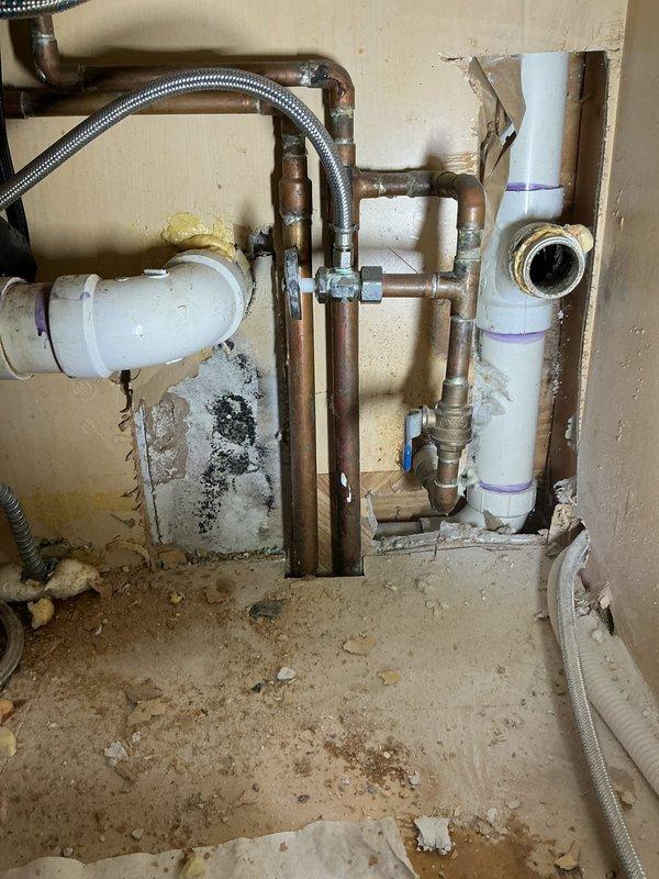 Accessed kitchen wall cavity to investigate reported drain leak. Exposed and inspected plumbing system, including P-trap assembly, PVC and copper piping connections. Identified and repaired leaking drain section, addressing water damage to surrounding wall material.