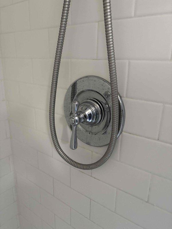 Conducted comprehensive assessment for multi-component plumbing quote including water heater replacement, kitchen faucet installation, and shower cartridge/head replacement. Inspected existing shower control assembly with chrome single-lever handle mounted on white subway tile wall; noted functioning flexible stainless steel supply lines requiring no immediate replacement. Documented current installation conditions with photographs to support detailed estimate preparation.