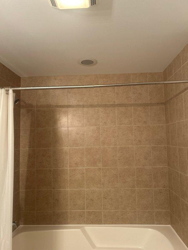 Performed bathroom remodel estimate for residential client. Inspected existing bathroom features including white porcelain bathtub with chrome fixtures, white toilet, and beige/tan tile surround extending from floor to walls. Documented current condition of fixtures and tile work with photos for estimate preparation.