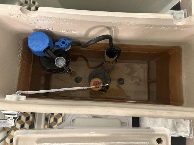 Addressed running toilet issue in century-old home by inspecting tank components, finding discoloration and mineral deposits causing malfunction. Replaced worn fill valve assembly and cleaned sediment from tank, restoring proper function and eliminating continuous water flow.