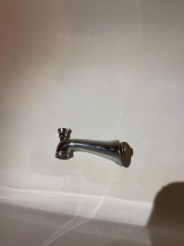 Responded to service call regarding detached bathtub spigot. Upon inspection, discovered the circular mounting collar had separated from the wall, causing the entire faucet assembly to disconnect. Installed new mounting hardware and secured replacement chrome tub spout with proper diverter functionality, restoring normal operation.