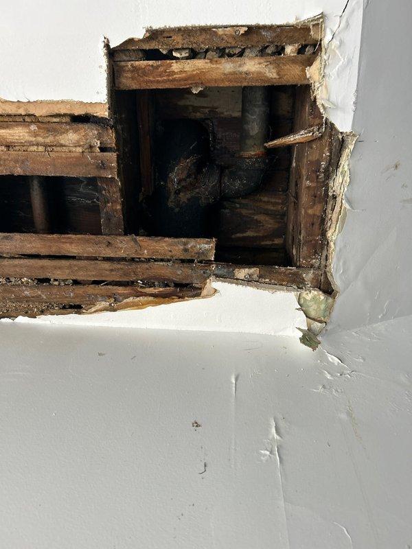 Investigated toilet leak reported to be affecting lower floor bathroom. Upon inspection, discovered significant water damage in ceiling and wall cavity below the toilet. Removed damaged drywall section to expose compromised wooden structural members showing signs of extensive water damage and deterioration. Documented damage with photos for further assessment and repairs.