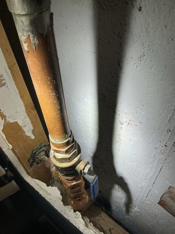 Investigated sinkhole in yard to determine source of water leak. Inspected copper supply line showing significant corrosion and deterioration at connection points. Located compromised pipe section near brick exterior wall where water was escaping and causing soil erosion beneath landscaping area.