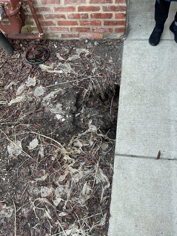 Investigated sinkhole in yard to determine source of water leak. Inspected copper supply line showing significant corrosion and deterioration at connection points. Located compromised pipe section near brick exterior wall where water was escaping and causing soil erosion beneath landscaping area.