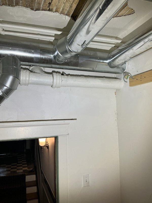 Conducted inspection of residential basement in response to reported persistent sewer odor. Examined PVC drain pipe connections and fittings at wall junction where green level indicator is present. Inspected HVAC ductwork and surrounding area for potential cross-contamination issues. Photos taken of plumbing configuration and adjacent utility spaces for assessment of remediation options to resolve ongoing sewer smell.