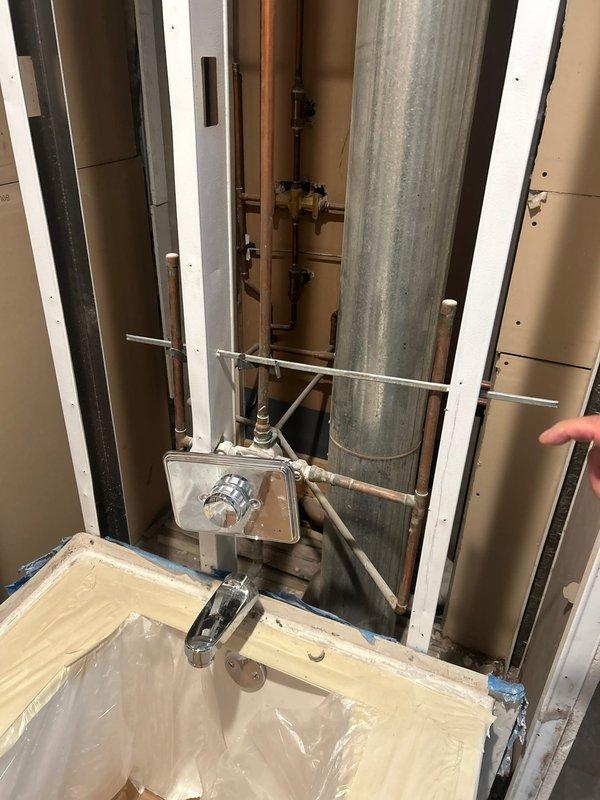 Installed two bathroom sink faucets and one shower faucet in partially constructed bathroom with exposed plumbing infrastructure. Installed new wax ring and reconnected kitchen faucet and garbage disposal unit, verifying proper drainage through P-trap assembly and ensuring no leaks in the system.
