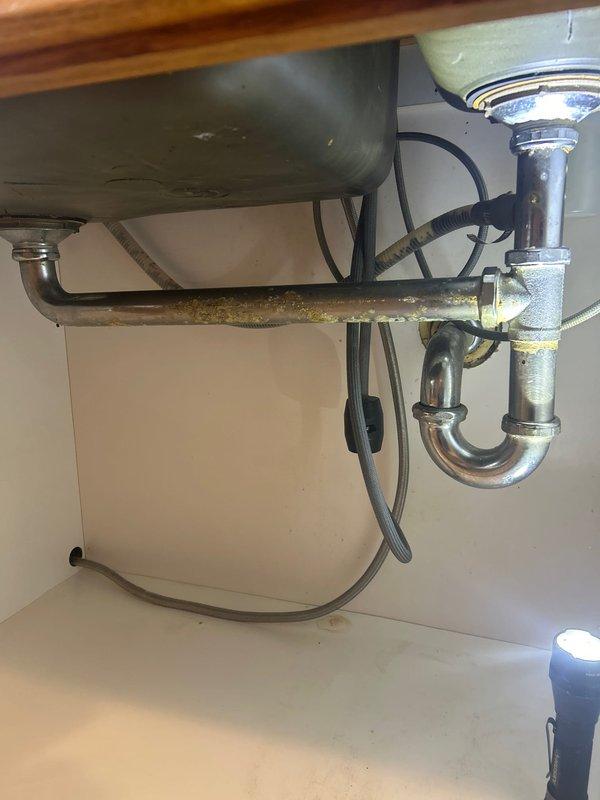 Completed VIP maintenance service on tankless water heater system, including descaling and inspection of components. Repaired broken drain pipe under double sink which showed significant corrosion and mineral buildup, replacing the affected P-trap assembly and horizontal drain section to resolve active leak.