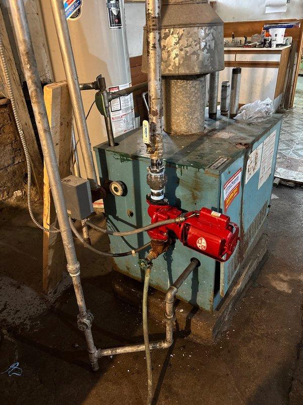 Completed inspection of aging boiler system with visible corrosion and wear. Examined pipe assembly with multiple valves and fittings connected to pump component. Documented condition of water heater, associated plumbing connections, and electrical components for future repair work.