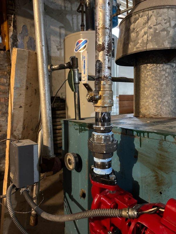 Completed inspection of aging boiler system with visible corrosion and wear. Examined pipe assembly with multiple valves and fittings connected to pump component. Documented condition of water heater, associated plumbing connections, and electrical components for future repair work.
