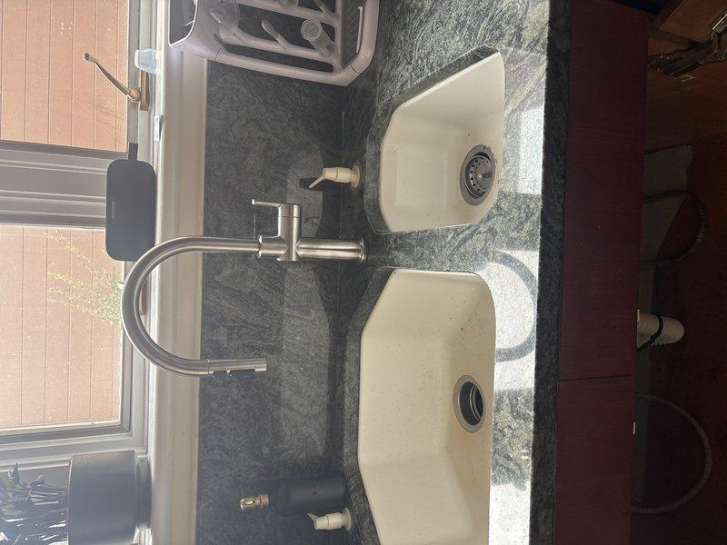 Completed installation of new double basin kitchen sink and faucet assembly as per sold repair agreement. Replaced corroded water supply lines and drain plumbing, addressing visible water damage to cabinet substrate. Job commenced after receiving required deposit as specified in service contract.