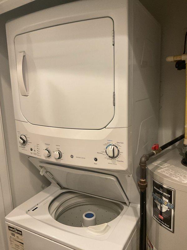 Conducted inspection of existing water heater (manufactured 2012) for potential replacement. Unit is installed in utility closet alongside stacked washer/dryer. Current installation includes standard PVC and copper plumbing connections with pressure release valve. Customer requests estimate for full replacement of aging unit.
