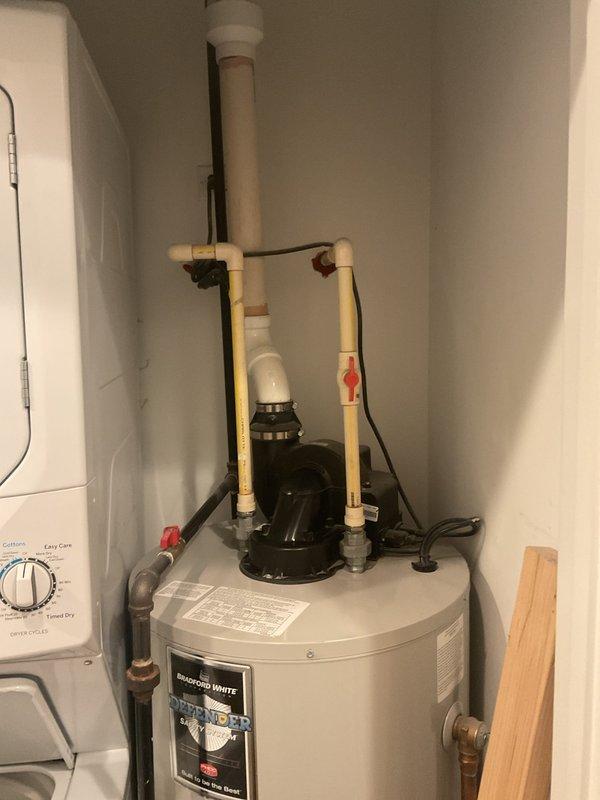 Conducted inspection of existing water heater (manufactured 2012) for potential replacement. Unit is installed in utility closet alongside stacked washer/dryer. Current installation includes standard PVC and copper plumbing connections with pressure release valve. Customer requests estimate for full replacement of aging unit.