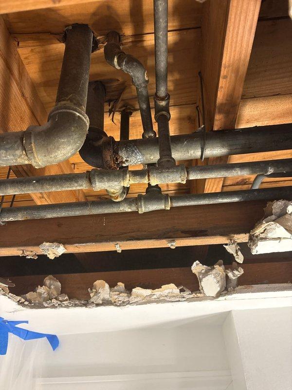 Completed repair of corroded pipe joints in ceiling area as scheduled. Exposed plumbing system by removing damaged ceiling material to access failed connections between metal pipes running across wooden joists. Replaced deteriorated sections and restored proper function to the plumbing system.