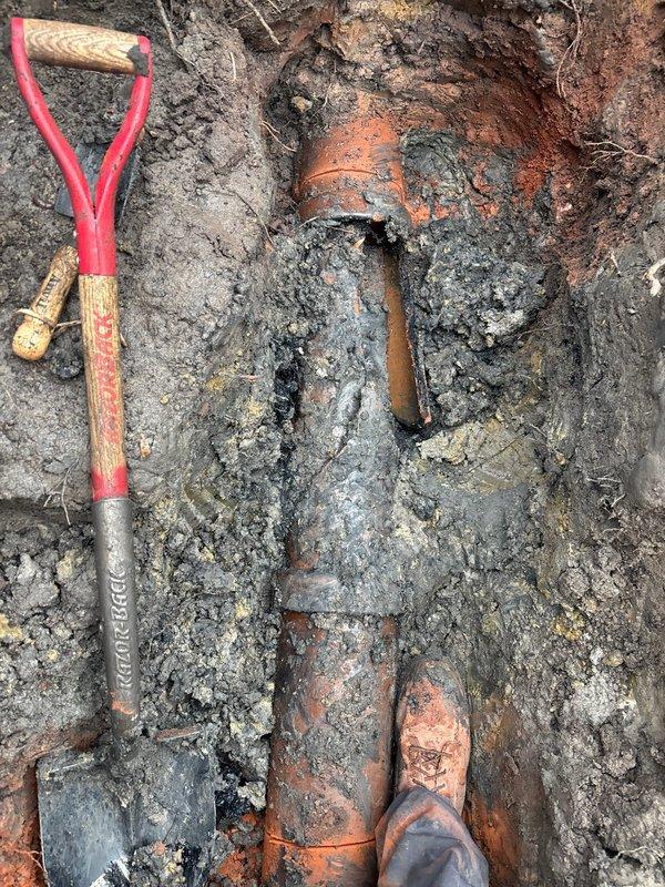 Excavated access to deteriorated clay sewer line, exposing the damaged sections for inspection and repair. Installed landscape fabric to protect surrounding area during work and created proper utility access point through paved surface to facilitate service of the drainage system.