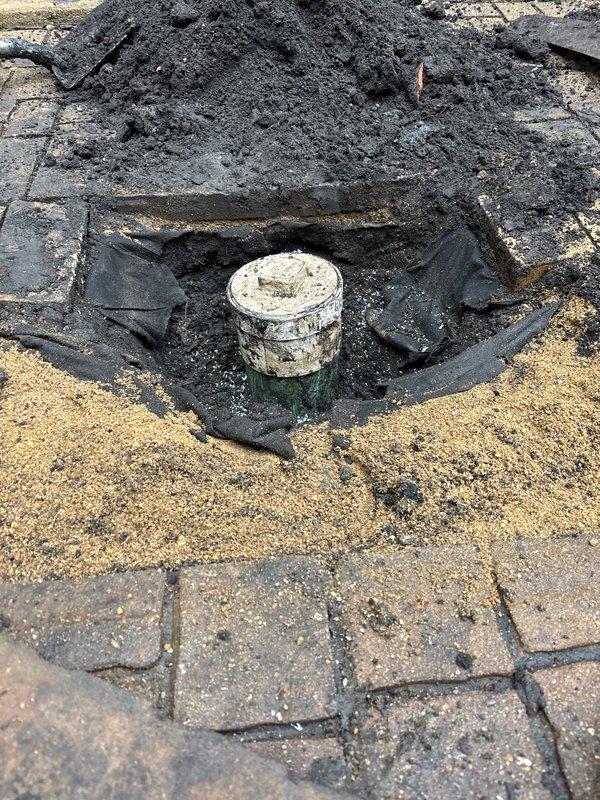 Excavated access to deteriorated clay sewer line, exposing the damaged sections for inspection and repair. Installed landscape fabric to protect surrounding area during work and created proper utility access point through paved surface to facilitate service of the drainage system.