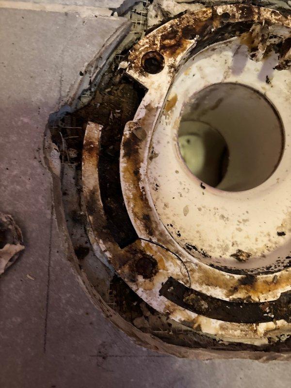 Diagnosed severe deterioration of toilet flange and surrounding subfloor in second-floor condo causing leak to downstairs unit when flushed. Documented extensive water damage, rust, and biological growth at fixture connection point with photographic evidence. Recommended complete replacement of toilet flange, repair of compromised subfloor, and proper sealing to prevent further leakage.