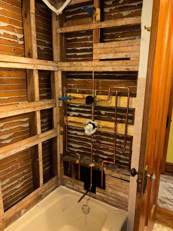 Completed rough-in plumbing installation for shower/tub, including copper supply lines, pressure regulator, and necessary valves. Installed valve body assembly and verified proper positioning of all components prior to wall closure. Will return after customer completes tile work for fixture installation and final connections.