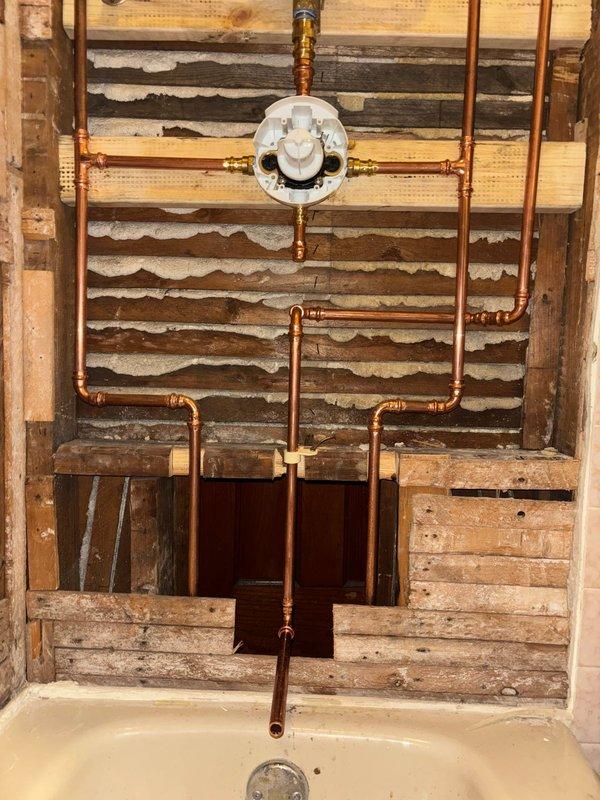 Completed rough-in plumbing installation for shower/tub, including copper supply lines, pressure regulator, and necessary valves. Installed valve body assembly and verified proper positioning of all components prior to wall closure. Will return after customer completes tile work for fixture installation and final connections.