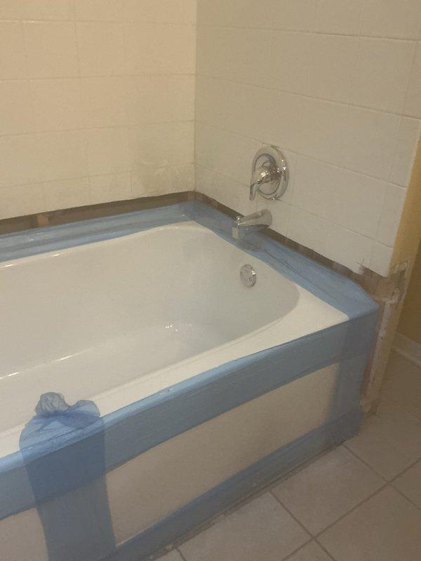 Completed shower and bathtub renovation including installation of new tile walls, mounting of chrome showerhead and control handles, and preparation of surfaces with protective coverings. Final inspection confirmed proper fixture installation and water flow functionality prior to completion.