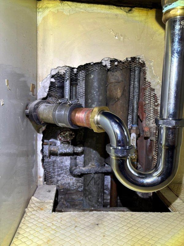 Completed warranty service to address kitchen sink leakage issue. Reconnected drain pipe that had become disconnected, verified proper P-trap alignment, and ensured secure connection between chrome, brass, and copper pipe sections. Noted significant wall damage around plumbing access area that should be addressed separately.