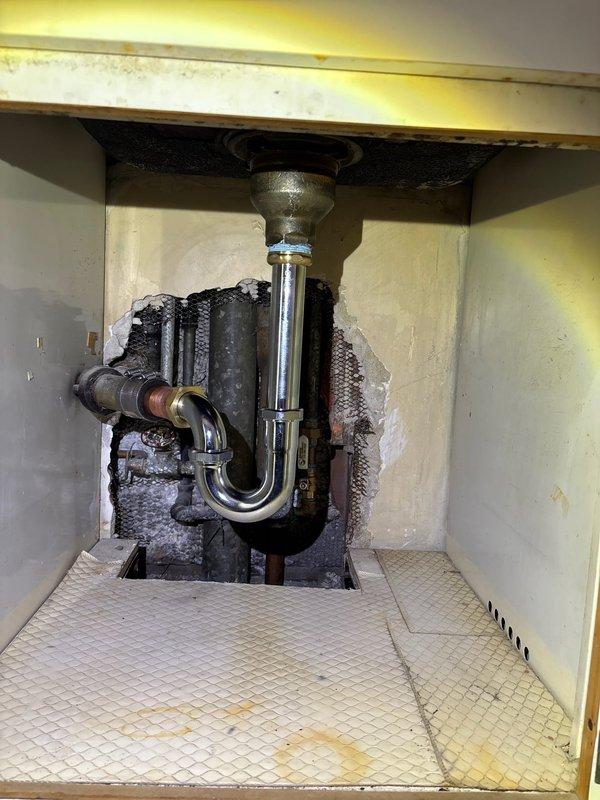 Completed warranty service to address kitchen sink leakage issue. Reconnected drain pipe that had become disconnected, verified proper P-trap alignment, and ensured secure connection between chrome, brass, and copper pipe sections. Noted significant wall damage around plumbing access area that should be addressed separately.