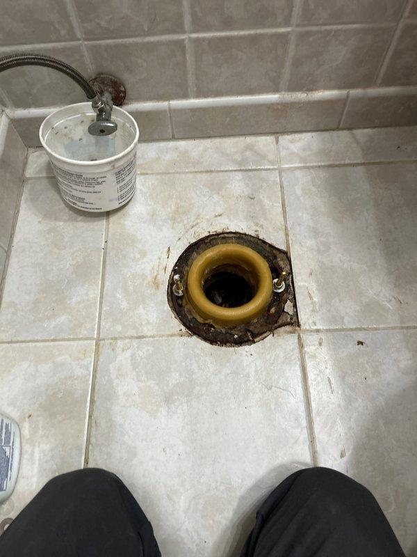 Responded to customer complaint of suspected toilet leak affecting neighboring unit in 80-year-old home. Upon inspection, removed toilet to examine wax ring, which showed deterioration and water damage around the flange area with visible staining. Replaced damaged wax ring, cleaned flange mounting area, and reinstalled toilet with new sealing components to prevent further leakage.