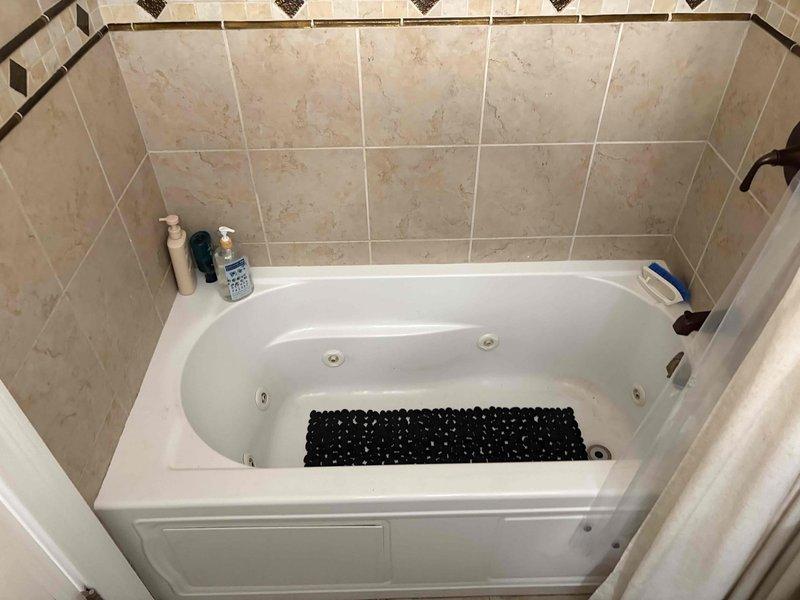 Conducted inspection of bathroom jetted tub and shower area to assess drainage system. Documented existing fixtures including bronze-finished faucet hardware and evaluated current drain configuration. Prepared comprehensive estimate for recommended drain and sewer service options based on visual inspection findings.