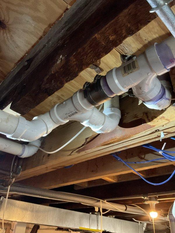 Successfully replaced failed PVC elbow seal in main drain line located in basement. Applied proper purple primer to all connection points and installed new fitting to restore proper drainage function. Verified system integrity with all joints properly sealed and secured to joists.