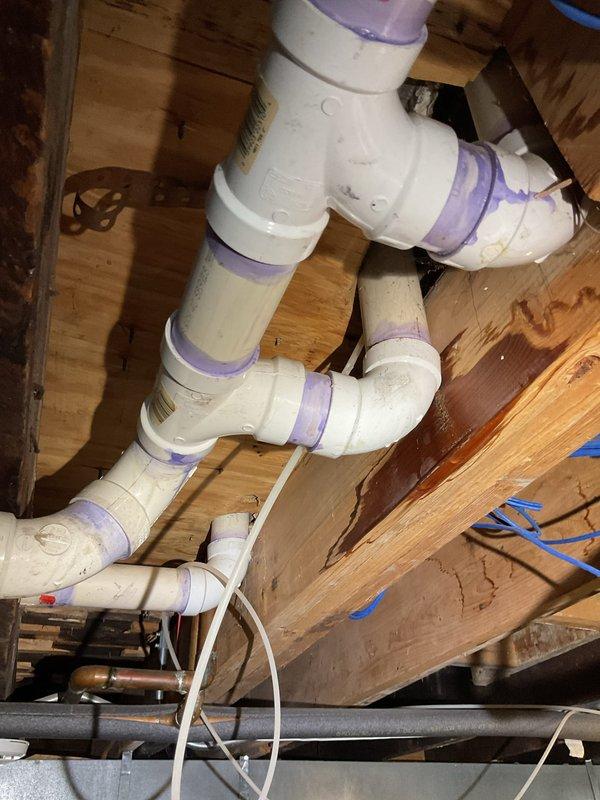 Successfully replaced failed PVC elbow seal in main drain line located in basement. Applied proper purple primer to all connection points and installed new fitting to restore proper drainage function. Verified system integrity with all joints properly sealed and secured to joists.