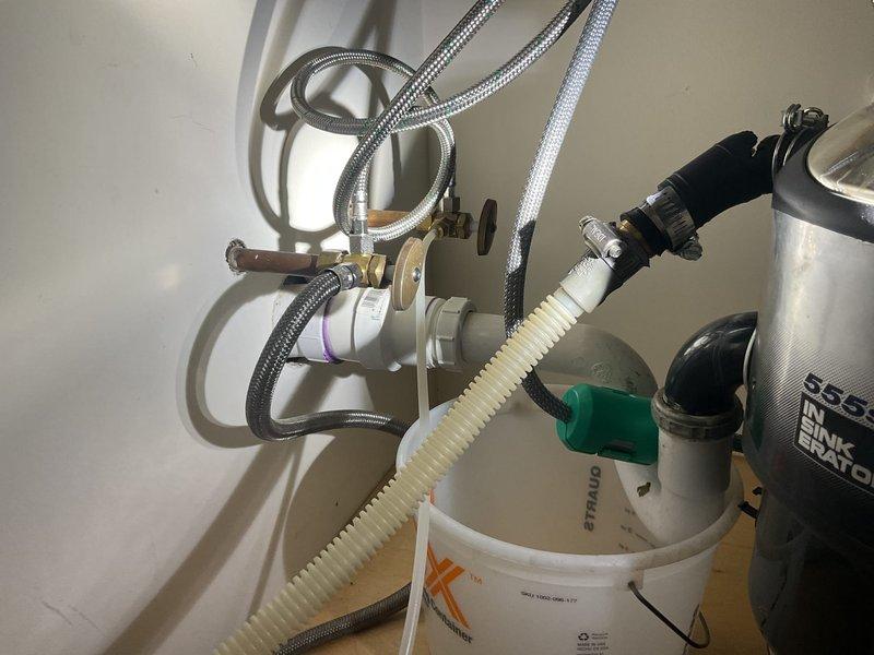 Responded to service call for leaking kitchen sink in 50-year-old multi-unit residential building. Upon inspection, discovered compromised seal at P-trap connection causing water leakage. Removed existing corrugated drain pipe, cleaned connection points, installed new PVC P-trap assembly with proper seals, and verified proper drainage with no leaks after repair.