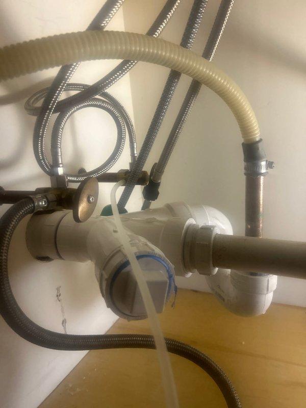 Responded to service call for leaking kitchen sink in 50-year-old multi-unit residential building. Upon inspection, discovered compromised seal at P-trap connection causing water leakage. Removed existing corrugated drain pipe, cleaned connection points, installed new PVC P-trap assembly with proper seals, and verified proper drainage with no leaks after repair.