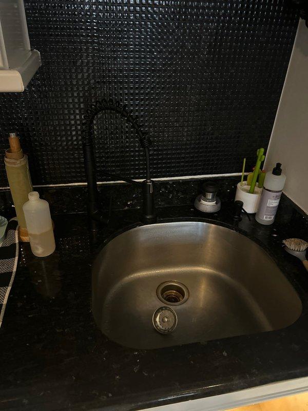Diagnosed and repaired kitchen faucet leaking from underneath by replacing worn O-rings and tightening loose supply line connections. Tested water flow and drainage after repair, confirming complete resolution of the leak that had been ongoing for over a week.