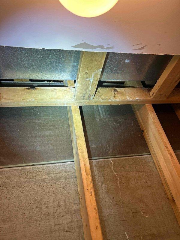 Conducted thorough inspection of ceiling area exhibiting water damage, identifying a leak source affecting wooden joists and insulation. Exposed ceiling structure revealed moisture infiltration with visible deterioration around light fixture installation. Successfully located leak origin and documented damage extent with comprehensive photo documentation for repair assessment.