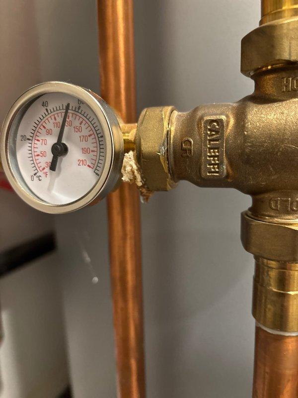 Installed and calibrated new Caleffi thermostatic mixing valve assembly with temperature gauge on existing copper pipe system in mechanical room. Verified proper operation with temperature reading approximately 90-100°F and inspected all connections for leaks. System now functioning correctly with appropriate pressure readings on gauge.