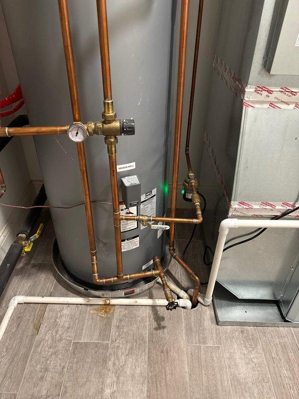 Installed and calibrated new Caleffi thermostatic mixing valve assembly with temperature gauge on existing copper pipe system in mechanical room. Verified proper operation with temperature reading approximately 90-100°F and inspected all connections for leaks. System now functioning correctly with appropriate pressure readings on gauge.