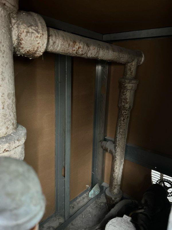 Inspected sump pump area after reports of odor. Discovered significant corrosion on horizontal pipe with rust deposits indicating long-term moisture exposure. Noted deterioration of metal components in the confined space requires attention to prevent system failure.
