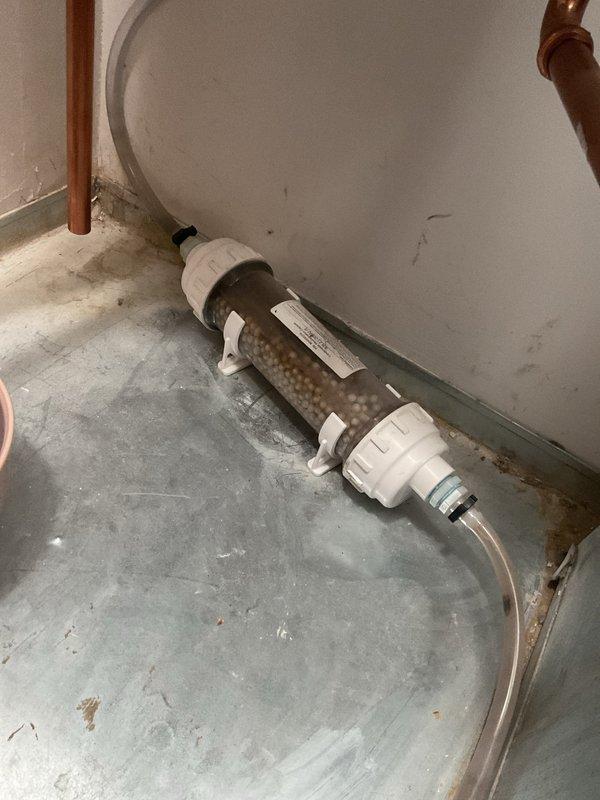 Inspected water treatment system with cylindrical filter containing beige media and verified proper installation with copper pipe connections. Conducted pressure testing using dual port manometer, obtaining readings of 6.97 inWC on both ports. Confirmed availability of Navien parts and advised customer that scheduling for installation is required.