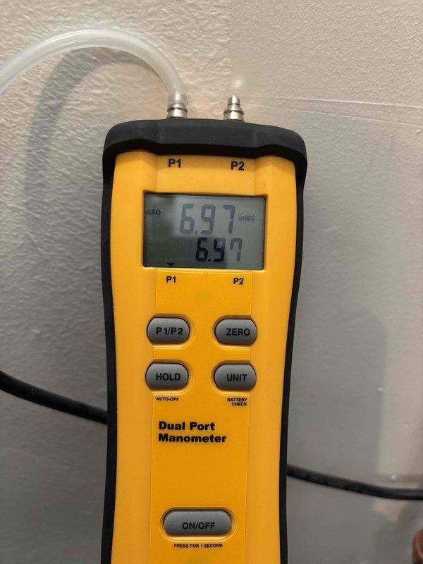 Inspected water treatment system with cylindrical filter containing beige media and verified proper installation with copper pipe connections. Conducted pressure testing using dual port manometer, obtaining readings of 6.97 inWC on both ports. Confirmed availability of Navien parts and advised customer that scheduling for installation is required.
