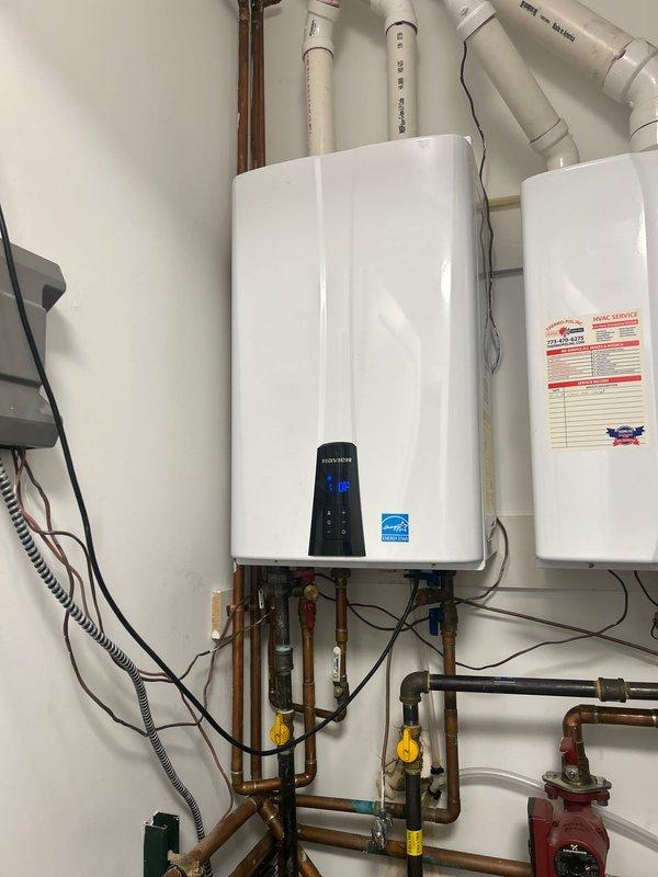 Responded to service call for a tankless water heater showing signs of water damage. Inspection revealed significant moisture damage and staining around mounting bracket with possible mold/rust development. Installed Navien kit and performed complete system flush using tankless flushing kit to restore proper functionality.