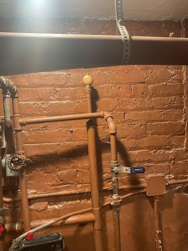Inspected property in response to reported water intrusion from floors. Examined copper plumbing infrastructure in utility area and identified corrosion on pipes running along ceiling junction in adjacent room. Determined water source and cleared blockage causing backup into church floor areas where no floor drains exist.