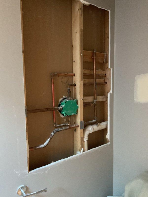 Removed drywall to access plumbing for shower/tub installation, exposing copper supply lines and drainage system. Installed green valve fixture and prepared the area for vanity installation in phase 2 of the project, which will commence upon client notification.