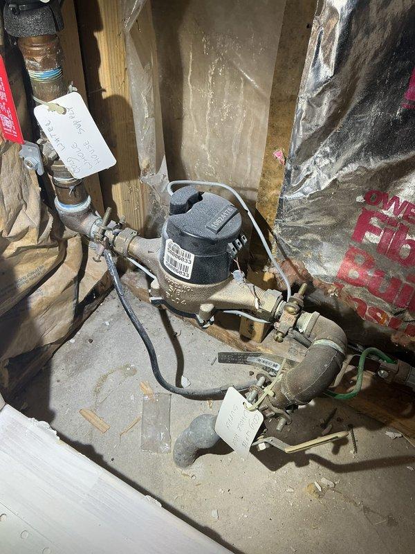 Conducted assessment for lead service line replacement as requested. Inspected exterior access point (metal utility cover) and interior water meter installation. Evaluation completed of existing piping system showing aged copper/brass components with visible tarnishing, requiring priority replacement of lead supply line.