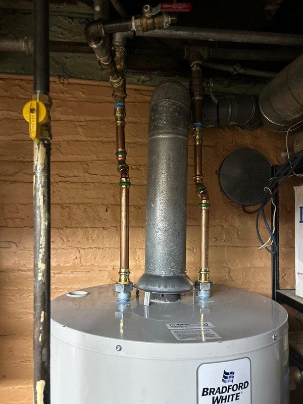 Successfully completed same day emergency installation of a Bradford White water heater in basement utility area. Installation included proper connection of copper pipes with brass fittings, installation of shut-off valves, and connection of metal exhaust vent pipe. New unit is operational with all appropriate plumbing connections secured and tested.